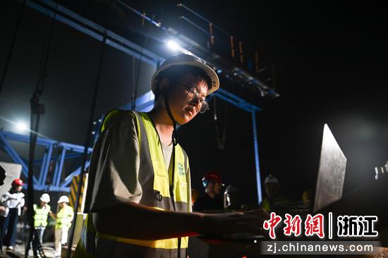 
图为：工作人员在跨百步亭港T构连续梁合龙现场调整智能张拉设备。中新社记者 王刚 摄
