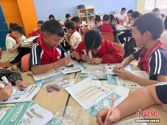 贵州黔南的“追光课堂”上，孩子们用100倍显微镜观察衣料结构。　新基石科学基金会供图