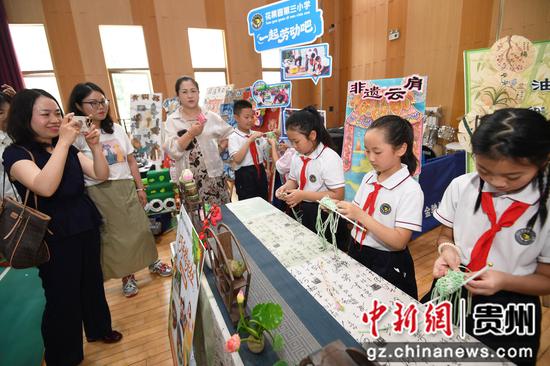 6月5日，贵阳市南明区中小学、幼儿园劳动教育实践技能展演活动现场，教师代表正观摩学生制作粽子手包。