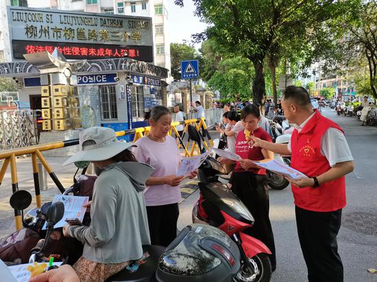 图为志原者正在柳州市柳邕第三小学校门口向等候接小孩放学的家长宣传电子烟危害活动。韦伟 摄 图为志原者正在柳州市柳邕第三小学校门口向等候接小孩放学的家长宣传电子烟危害活动。韦伟 摄