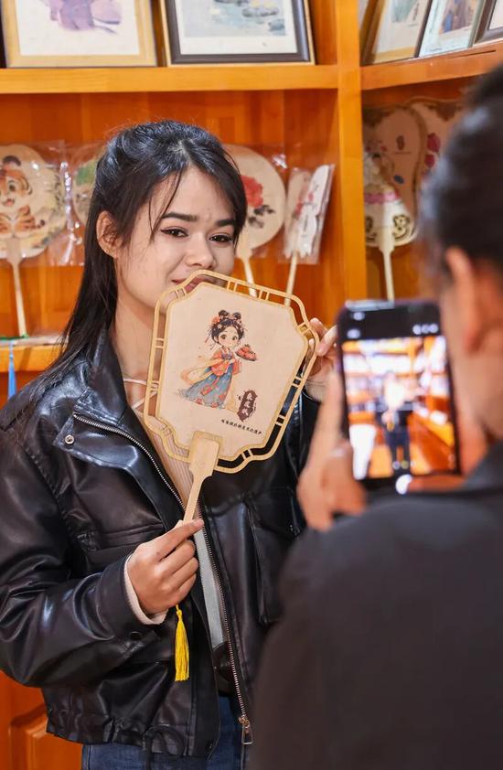 墨玉县90后返乡大学生穆耶赛尔·艾合麦提托合提展示桑皮纸文创产品。b