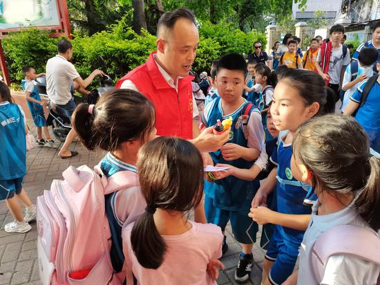 图为志原者正在柳州市柳邕第三小学校门口向小学生宣传电子烟危害。 韦伟 摄 图为志原者正在柳州市柳邕第三小学校门口向小学生宣传电子烟危害。 韦伟 摄