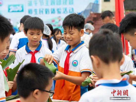 图为6月18日，贵州省罗甸县第二小学开展“2026端午节主题团建暨师生民俗体验”活动，学生、家长和教师一起包粽子。史传鸿 摄