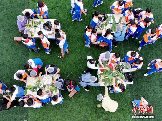 图为6月18日，贵州省罗甸县第二小学开展“2026端午节主题团建暨师生民俗体验”活动，学生、家长和教师一起包粽子。史传鸿 摄
