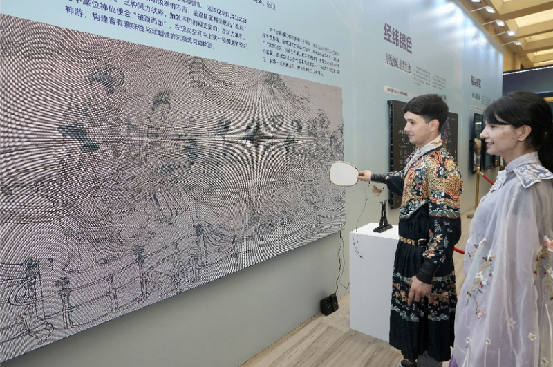 游客扇动扇子参与绘画创作，体验传统绘画的数字互动。克拉玛依融媒体记者 崔文娟 摄