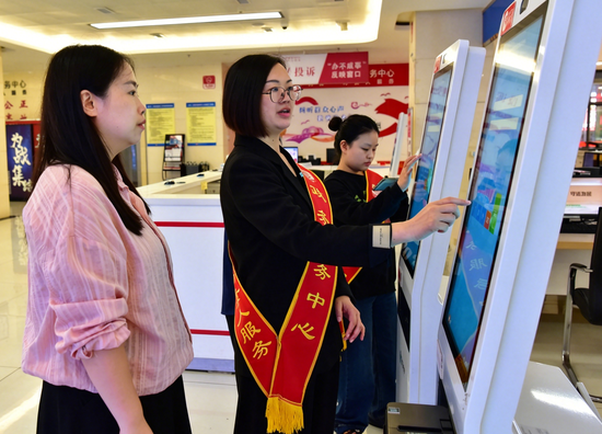 在黔西市人民政府政务大厅 工作人员正在为群众介绍相关办理流程。