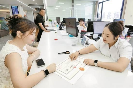 在师市政务服务中心二楼大厅办事窗口，工作人员为商户办理营业执照。王晓燕 摄