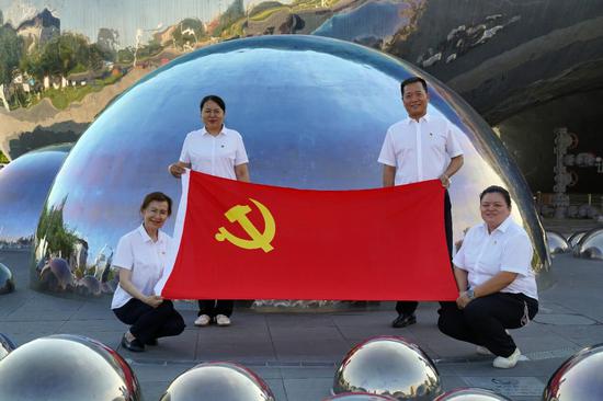 6月30日，克拉玛依一号井景区，迎宾花园社区居民与党旗合影。克拉玛依融媒记者 非尔代维斯·热夏提 摄