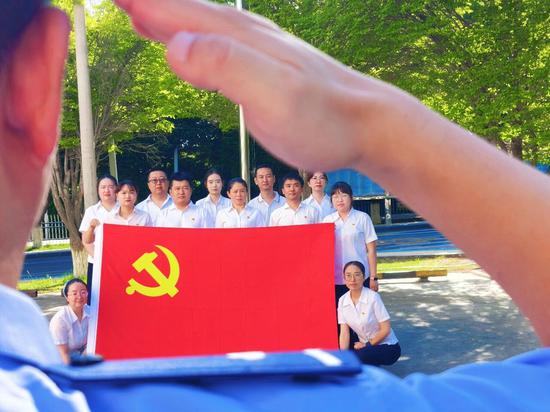 7月1日，独山子区西宁路街道第十社区党员及社区民警与党旗合影。魏荣娜 摄