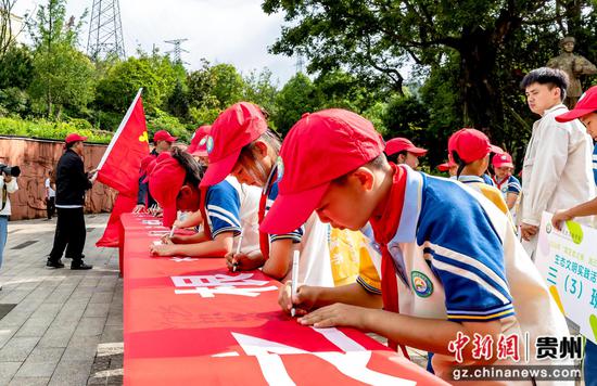 学生在贵州省黔西市凤凰山公园举行生态文明实践研学活动中进行环保签名。