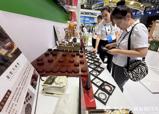 6月28日，在新疆国际会展中心投资合作专区和田展馆，参观者正在看展台上的合香珠手串。石榴云/新疆日报记者 拍热扎提·阿不都 摄