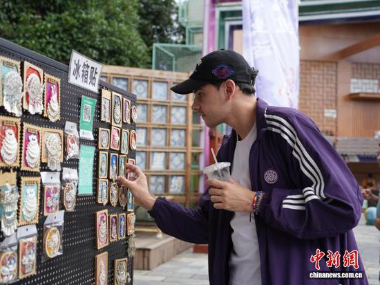 7月4日,贵州省凯里市苗侗风情园内,游客在绣里淘非遗集市挑选冰箱贴。中新社记者 周燕玲 摄 7月4日,贵州省凯里市苗侗风情园内,游客在绣里淘非遗集市挑选冰箱贴。中新社记者 周燕玲 摄