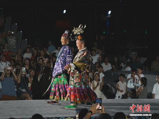 7月4日晚,贵州省凯里市苗侗风情园内,2位苗族老人携手走“村T”舞台。记者 周燕玲 摄 7月4日晚,贵州省凯里市苗侗风情园内,2位苗族老人携手走“村T”舞台。记者 周燕玲 摄