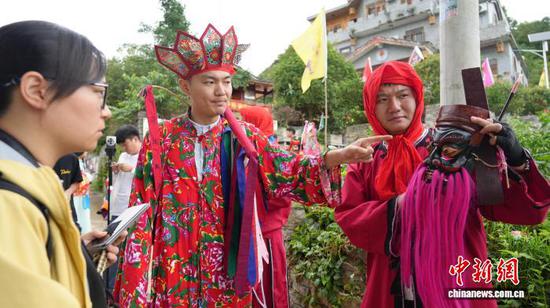 图为贵州傩文化传承人张勇 (中)向游客介绍黔南傩堂戏面具。石小杰 摄 图为贵州傩文化传承人张勇 (中)向游客介绍黔南傩堂戏面具。石小杰 摄