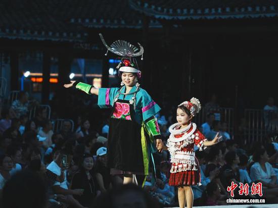 7月4日晚,贵州省凯里市苗侗风情园内,一对母女身穿民族服饰走上“村T”舞台。记者 周燕玲 摄 7月4日晚,贵州省凯里市苗侗风情园内,一对母女身穿民族服饰走上“村T”舞台。记者 周燕玲 摄