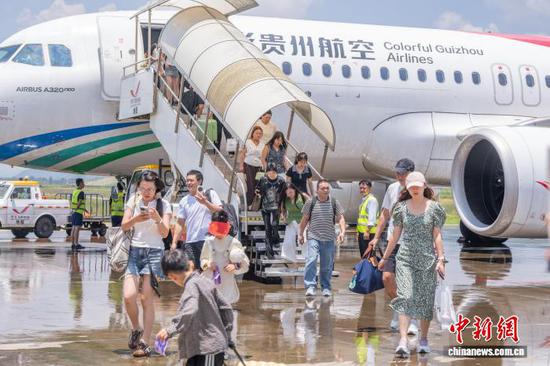 图为7月9日，在贵州省毕节市飞雄机场，旅客陆续走下飞机。罗大富 摄