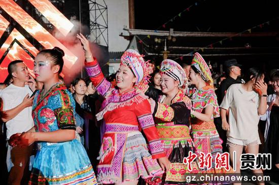 苗族同胞们正和大家一起围着篝火跳舞。