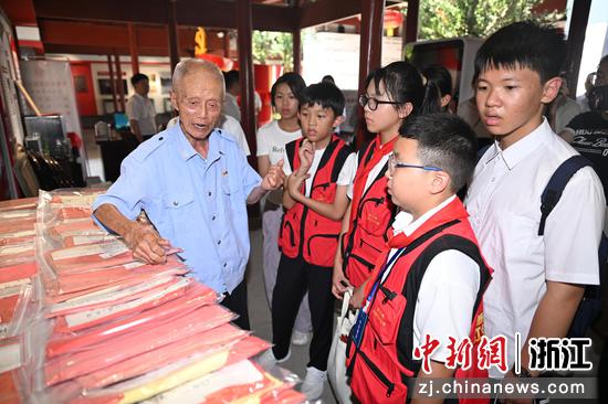 图为：在浙西南第一个中共党支部诞生地大柘镇泉湖寺，20年坚守“一个人的升旗仪式”的老党员朱宗鹤向探访团成员展示旧国旗。中新社记者 王刚 摄