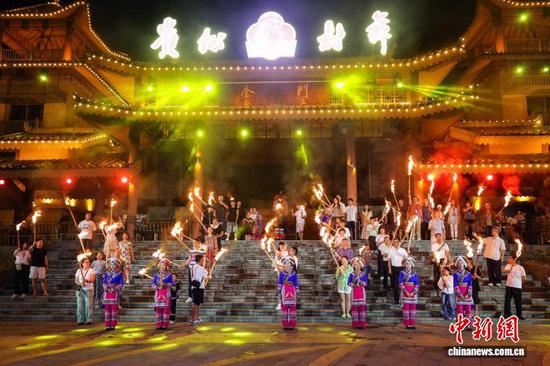 7月21日晚，游客参加彝族火把节体验。中新社记者 瞿宏伦 摄