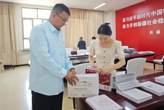 和田邮政工作人员与新疆和田学院教师现场核对大学录取通知书。通讯员 王洁 摄