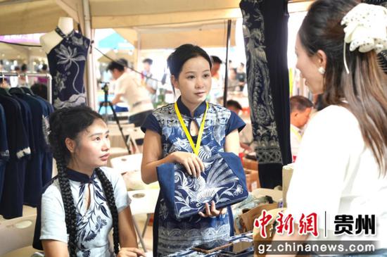 图为参展商家热情地向驻足游客介绍产品的特色。