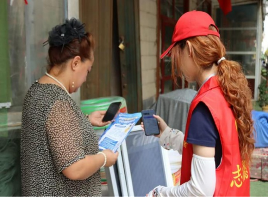 志愿服务团成员刘翔宇帮助商户下载国家反诈APP。刘浩博 供图