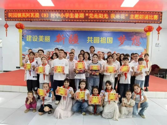 自治区人大常委会机关驻叶城县河园镇英阿瓦提村工作和村“两委”与参加朗诵比赛的学生合影。王梓燕 摄