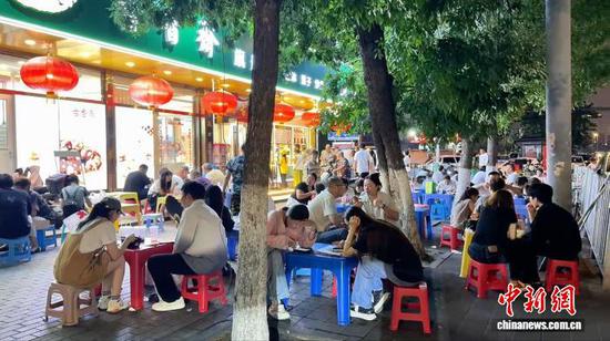 7月21日晚，天津街头刨冰店外座无虚席，市民与游客围坐街边品尝津味刨冰。入伏高温之下，特色刨冰吸引不少外地游客专程寻味。冯宏杰 摄
