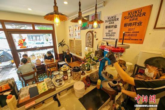 7月21日，天津街边一家刨冰店内，店员为顾客制作刨冰。中新社记者 佟郁 摄