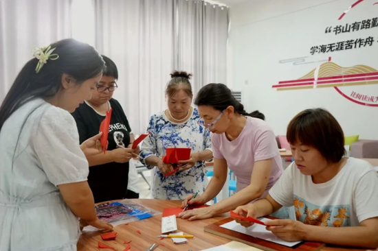 在火箭农场新时代文明实践所，学员正在认真学习剪纸技艺。王璇 摄