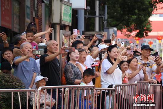 图为8月8日，黔南布依族苗族自治州成立70周年庆祝活动——民族团结大巡游现场，路边观众在拍摄巡游队伍。中新网记者 刘美伶 摄