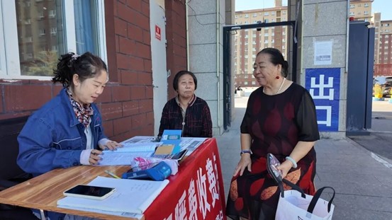 在欣晨嘉苑小区门口，博乐市阳光热力有限责任公司工作人员为小区居民办理缴纳采暖费服务。王腊梅 摄