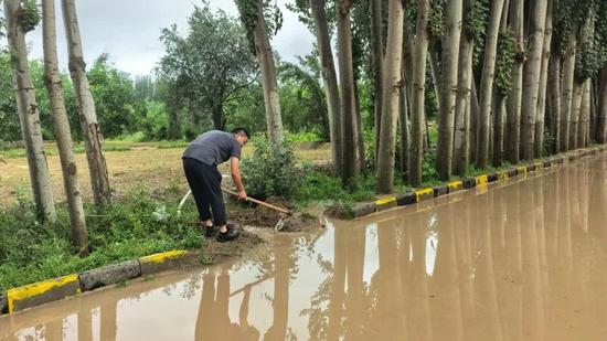 崔栗铜帮助群众清理道路积水，方便群众出行。a