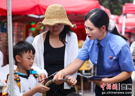 毕节市人民检察院百里杜鹃管理区检察室检察干警开展流动普法活动。图为检察干警正在给集市上的游客宣传预防诈骗、文明旅游以及未成年保护等法律知识。