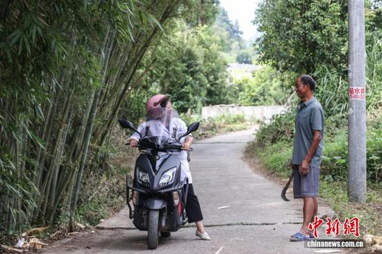 图为陈远秋骑车出诊时遇过路村民询问其病情。中新社记者 瞿宏伦 摄 图为陈远秋骑车出诊时遇过路村民询问其病情。中新社记者 瞿宏伦 摄