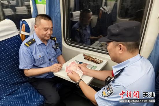 图为乘警帮助旅客找回丢失的现金和钱包。(北京铁路公安局天津公安处供图) 图为乘警帮助旅客找回丢失的现金和钱包。(北京铁路公安局天津公安处供图)