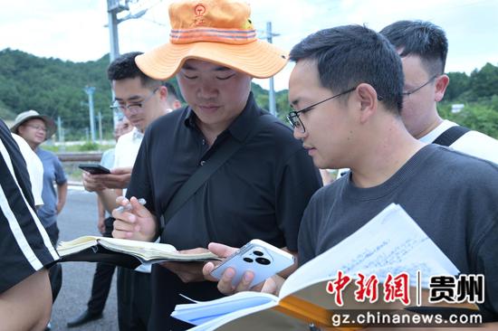 图为该段工作人员现场复核测量数据 。李明菲摄