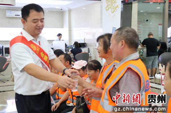 该行工作人员为环卫工人递上清水解渴。