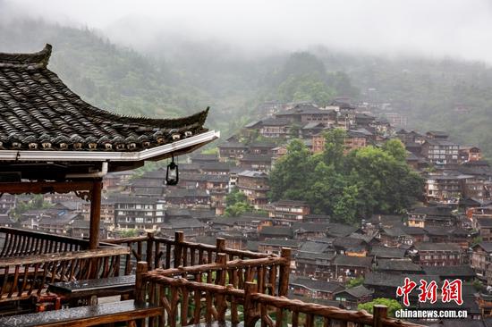 西江千户苗寨，细雨生雾，漫山云雾萦绕山谷。千余座吊脚楼顺着山势层叠排布，青瓦木楼在烟雨里若隐若现，勾勒出苗寨独有的山地建筑画卷。