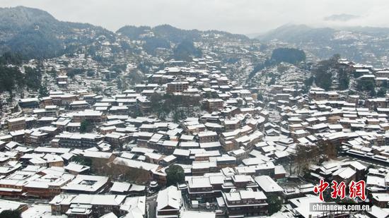 西江千户苗寨雪后初霁，依山而建的木质吊脚楼群覆上皑皑白雪，木屋青瓦与皑皑白雪相映，层层叠叠铺展于群山之间，勾勒出冬日苗寨独有的建筑景致。