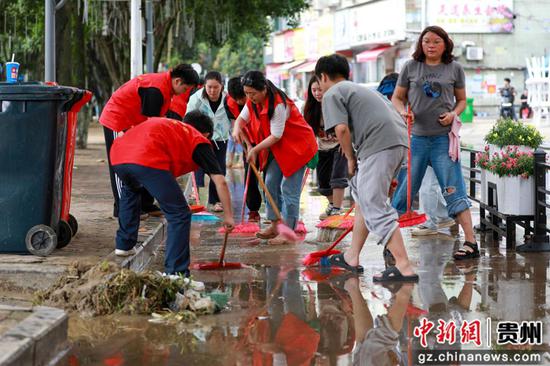 5月19日，都匀市群众志愿者在清理道路淤泥。