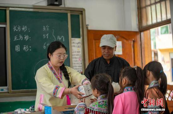 图为潘先锋(左二)、彭韩萍(左一)在乌英苗寨教学点给学生发放牛奶和梨子。吴德军 摄 图为潘先锋(左二)、彭韩萍(左一)在乌英苗寨教学点给学生发放牛奶和梨子。吴德军 摄