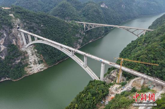 9月7日，贵州省瓮安县，航拍建设中的瓮马铁路乌江特大桥（前），该大桥全长520米。贵州瓮安至马场坪铁路（瓮马铁路）南北延伸线项目，作为贵州省重要的资源开发型铁路，共有桥梁114座，隧道56座，桥隧比为69%。其中，乌江特大桥、湘江特大桥等大桥作为全线控制性工程，修建难度大、技术要求高，建设者们克服困难，创新运用多项施工工艺，在崇山峻岭间架起了坚固通途。（无人机照片）