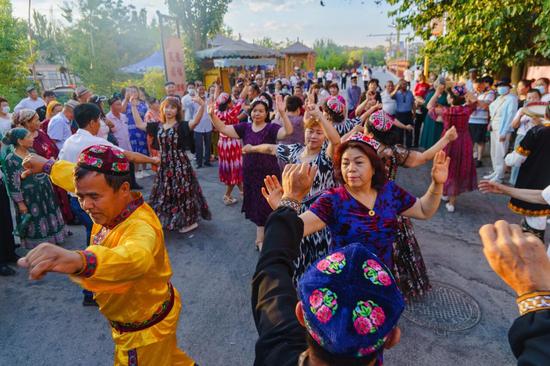 各民族群众在阿勒屯古街跳舞。（资料图）