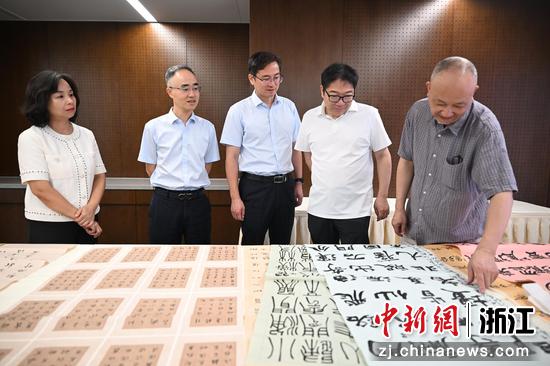 图为：中国人寿寿险浙江省分公司党委委员、副总经理胡永生（中）观看作品评审。中新社记者 王刚 摄