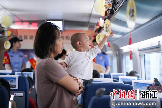 图为：旅客带孩子体验车厢内的中秋装置。中新社发 高艳 供图