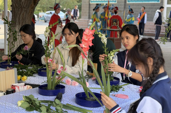 系列活动中，艺术节各展位遍布校园，图为该校的中式插花展位吸引众多学生参与体验。张家伟 摄