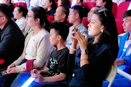 音乐会现场，观众沉浸在国乐旋律中，不时鼓掌喝彩，记录舞台精彩瞬间。努尔古再丽 摄