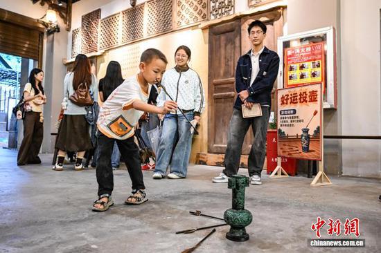 10月1日，孩童在汇川大院沉浸式怀旧街区体验投壶。中新社记者 瞿宏伦 摄