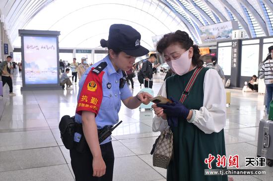 图为北京铁路公安局天津公安处天津西站派出所民警正在为旅客解答疑惑，热情为旅客服务。（北京铁路公安局天津公安处供图）